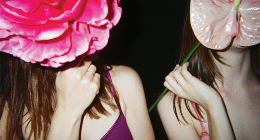 Women in bras holding large glass flowers over their faces.