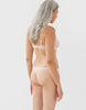 On model backside image of beige, organic cotton thong and bra. 