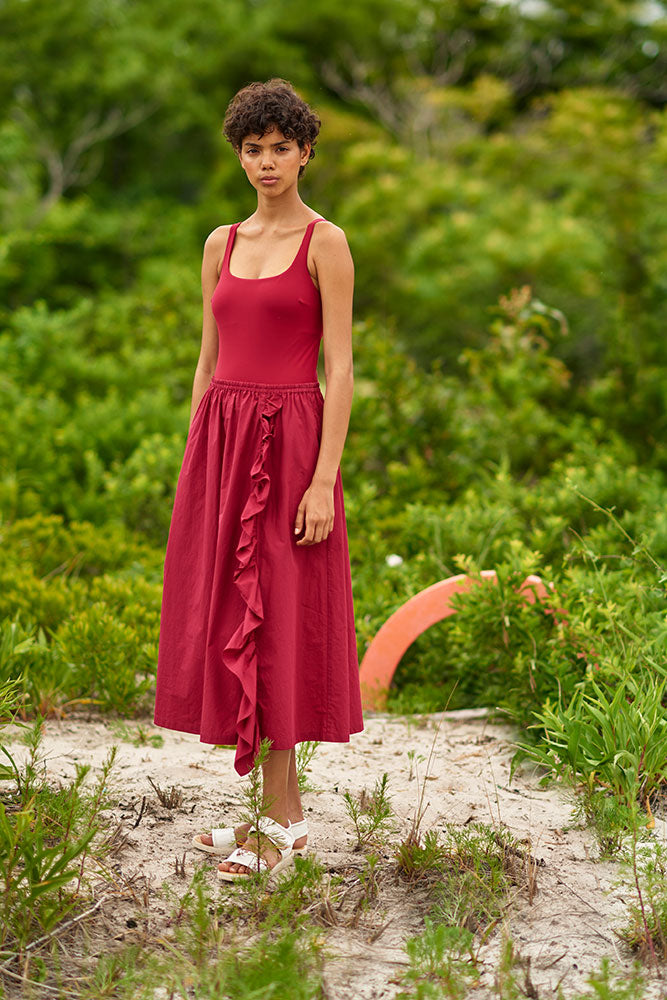 woman in grassy area wearing red one piece and matching skirt. 