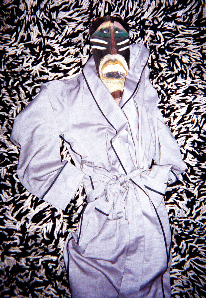 Gray robe laid on rug with mask placed at neck hole. 
