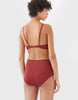 back of woman wearing red cotton wireless bralette with brown trim and matching high waist panty