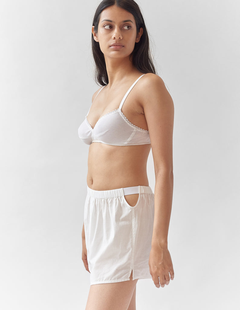 A woman wearing a white bra with white cotton boxer shorts.