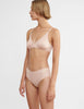 side view of woman wearing beige cotton wireless bralette and matching hipster panty by Araks