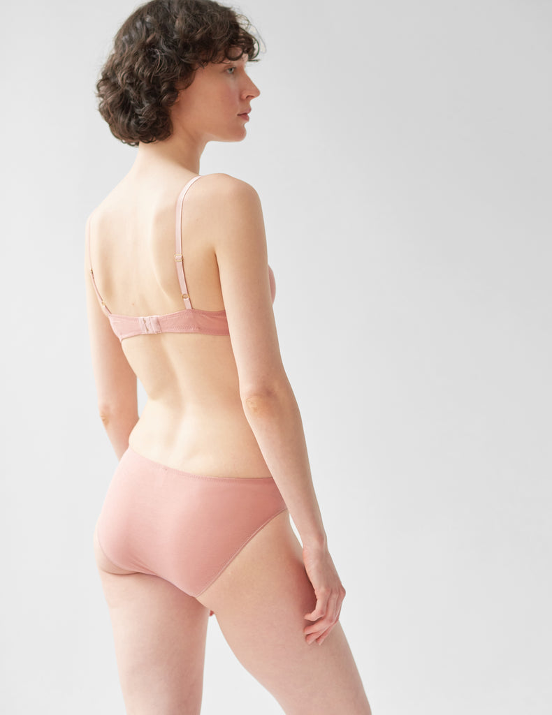 back of woman wearing pink cotton wireless bralette with purple silk and matching panty