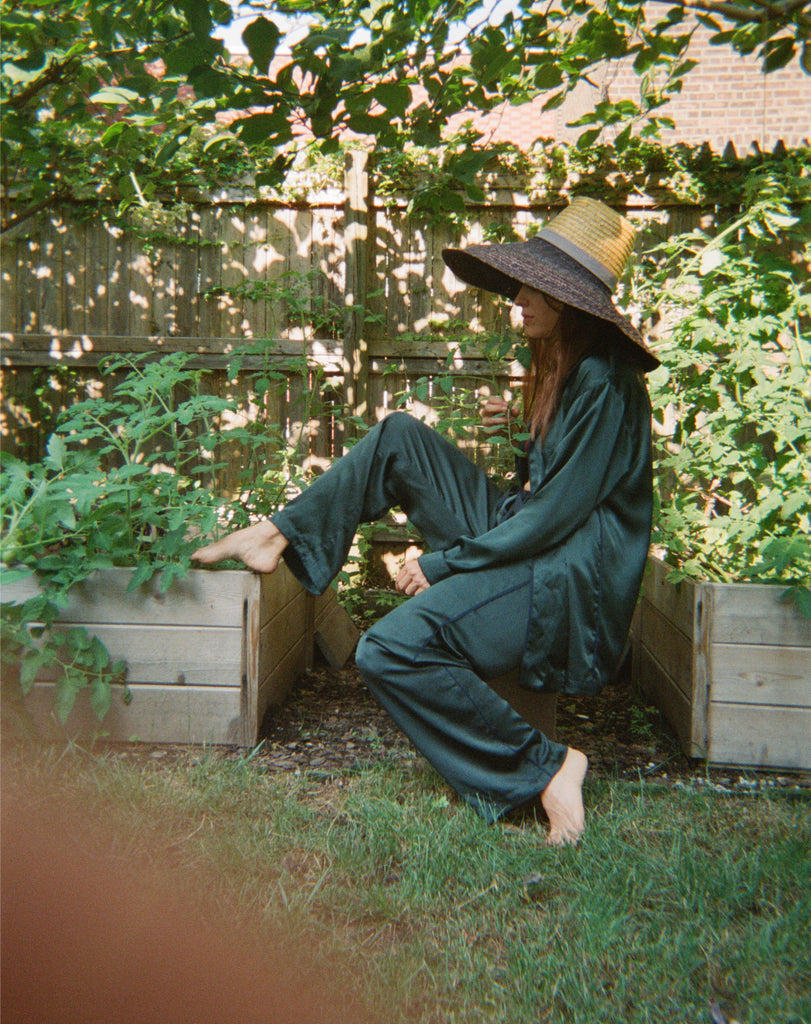 Woman in garden wearing green satin pajamas 