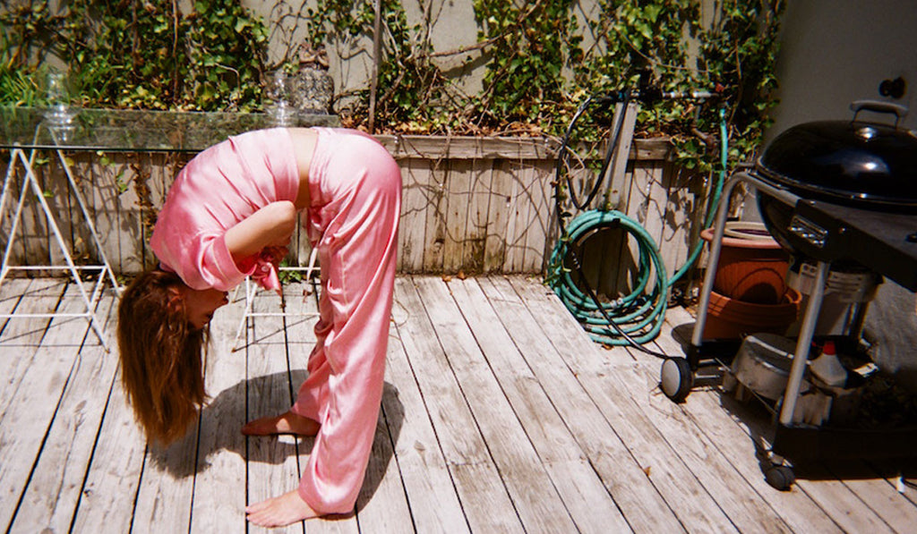 Model bend down on the porch, wearing pink sleep shirt and matching pink pants