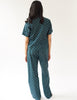 back of woman wearing green cotton pajama top with blue trim and polka dot print and matching pants by Araks