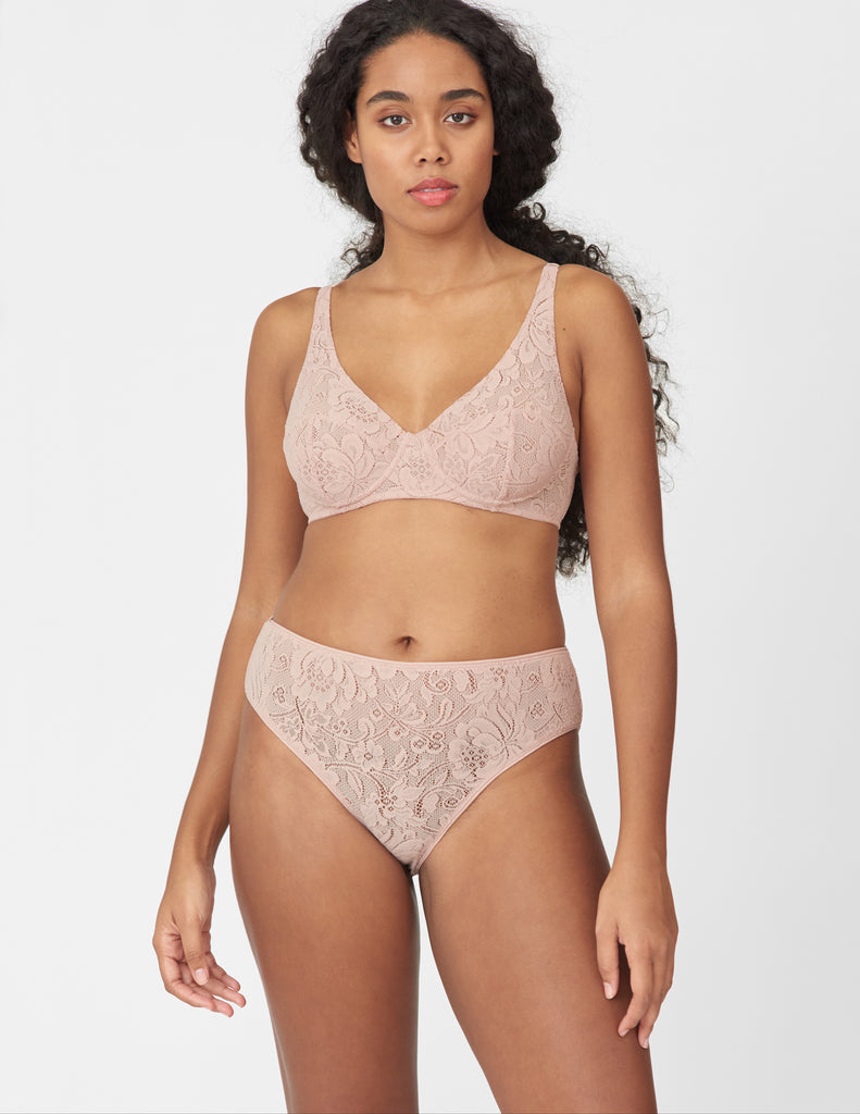 Front view of woman wearing beige, lace underwire bra and matching mid-rise panty.