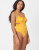 Three quarter view of woman wearing a yellow one piece swimsuit with side cut outs and a tie in back