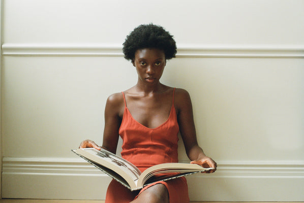 Woman in an orange slip reading a book.