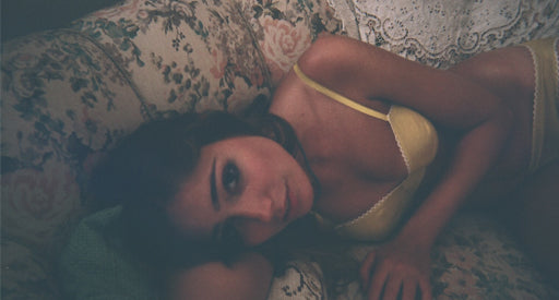 Woman in a white bra laying down on a floral couch.