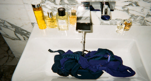 Blue clothing in a sink with the water running.