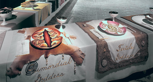 Table setting with a table cloth, plates, and wine glasses.