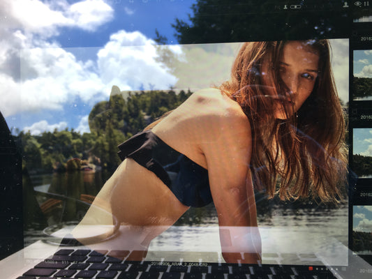 Reflection of a side view of a woman in a black bikini top.