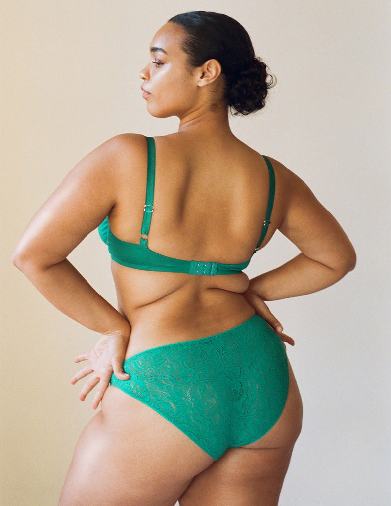 a model wearing the Tris panty in emerald green lace.