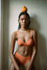 A model in the araks tamara bralette and tali hipster in mars orange