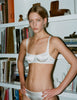 front view of woman wearing white silk bra and panty while posing in front of a bookshelf. 