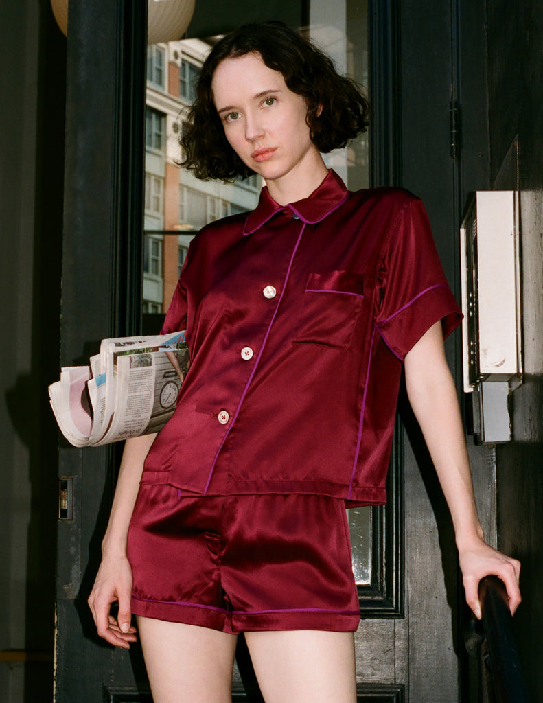 A woman modeling the Araks Shelby silk pajama top with the Tia pajama shorts in Garnet 