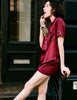 A woman modeling the Araks Shelby silk pajama top with the Tia pajama shorts in Garnet 