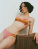 A model wearing the Willow Bralette and Saffi  Panty in orange and pink silk and cotton.