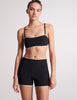 On model image of black bandeau swim top, with straps, with black swim shorts