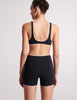 On model image of backside of black swim top and swim shorts