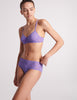 three quarter view on model of purple lace bra and panty