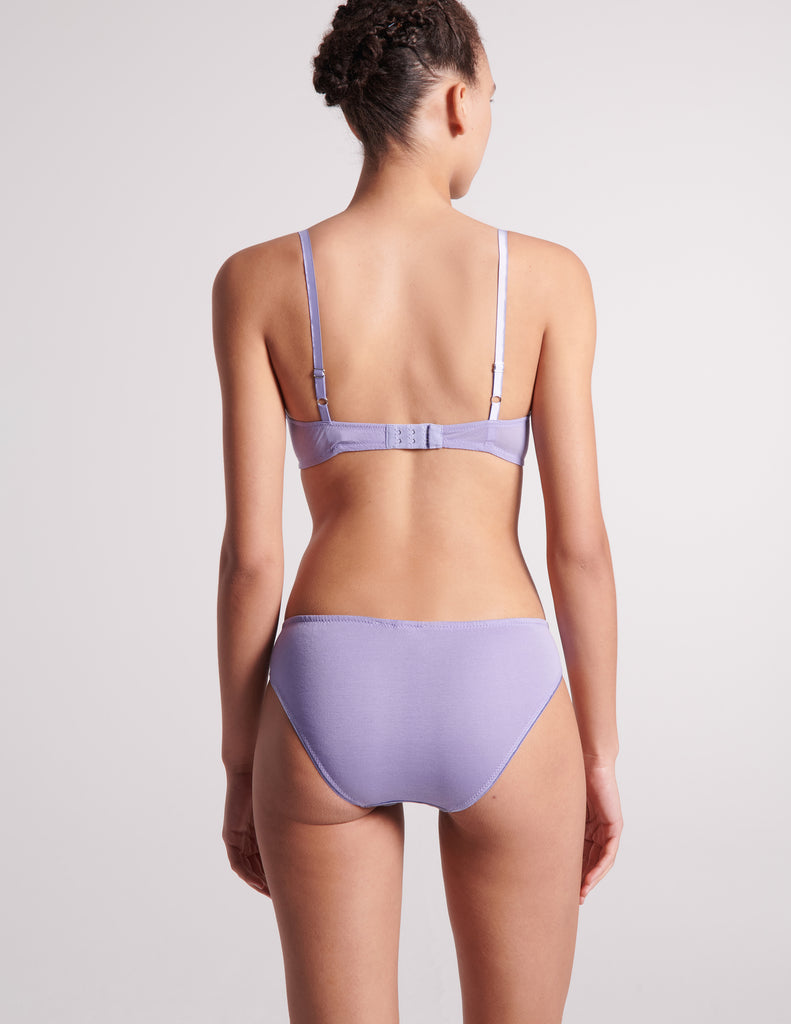 On model image of backside of blue cotton with purple silk bralette and blue cotton with purple silk panty.