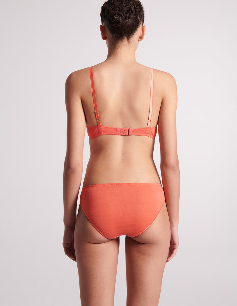 On model image of back of orange cotton with pink silk bralette and orange cotton with pink silk panty.