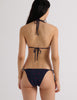 Model wearing the Araks Nelle bikini top and Nadia bikini bottoms in navy blue with red polka dots