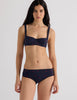 Model wearing Araks Ulija bikini top and Ezra bikini bottoms in navy with red polka dots