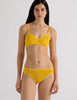 A model in the araks organic cotton stella thong in pomelo yellow