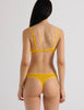 A model in the araks organic cotton stella thong in pomelo yellow