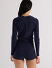 Model wearing Araks Undine rashguard with Polly swim shorts in navy with red polka dots