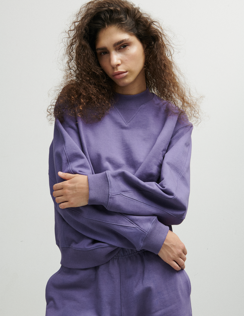 A model posing in the Araks Valerie crewneck in the shade Violette against a white background.