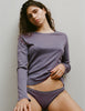 A model wearing a Sabine long sleeve top and Isabelle panties in Violette, standing against a plain light gray wall.