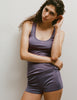 A model wearing a James tank top and Presley shorts in Violette, standing against a plain light gray wall.