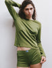 A model wearing the Sabine long sleeve top and the Presley short in Moss posed against a plain light gray wall.