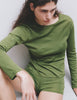 A model wearing the Sabine long sleeve top and the Presley short in Moss posed against a plain light gray wall.