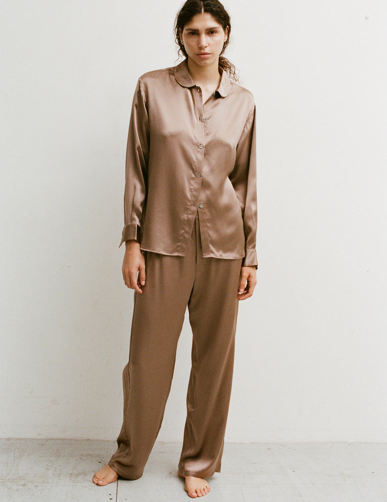A woman wearing an Araks Suki silk pajama top with Viktoria silk bottoms in Terra