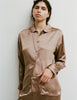 A woman wearing an Araks Suki silk pajama top with Viktoria silk bottoms in Terra