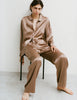 A woman wearing an Araks Suki silk pajama top with Viktoria silk bottoms in Terra