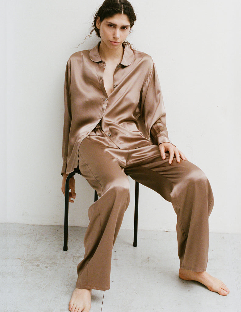A woman wearing an Araks Suki silk pajama top with Viktoria silk bottoms in Terra