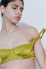 A model wearing the Araks silk Gita Bra in the shade Chartreuse posing against a white background. 