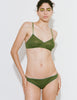A model shown wearing Araks Antonia bralette and stella thong in Moss set against a plain light gray background.