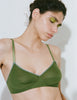 A model shown wearing Araks Antonia bralette in Moss set against a plain light gray background.