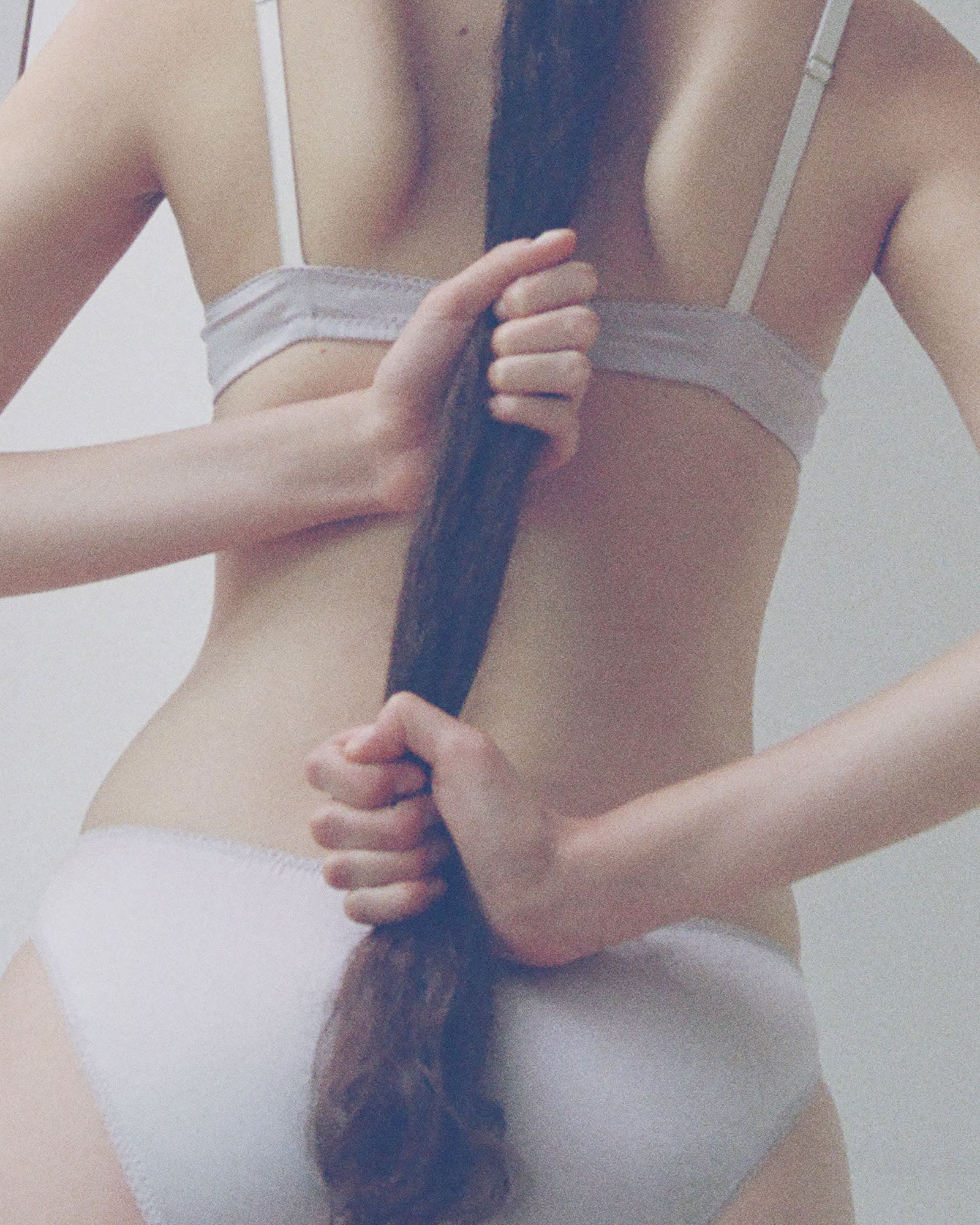 a model holding her ponytail in the araks silk gita underwire bra and gwyneth panty in fairy purple