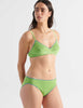 Three quarter view image of model wearing green cotton panties with blue trim and matching bralette. 