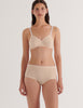 Woman wearing a beige Antonia bralette and mabel hipster set on a white background