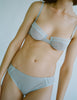 a model in the araks chloe underwire and sonja panty in mist grey with blue lace